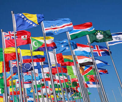 Flags of all nations of the world are flying in blue sunny sky